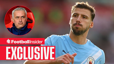 Ruben Dias playing for Man City looking left with Jose Mourinho sat in a dugout looking his way