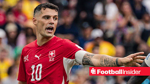 Granit Xhaka in action with left arm outstretched towards opponent and talking