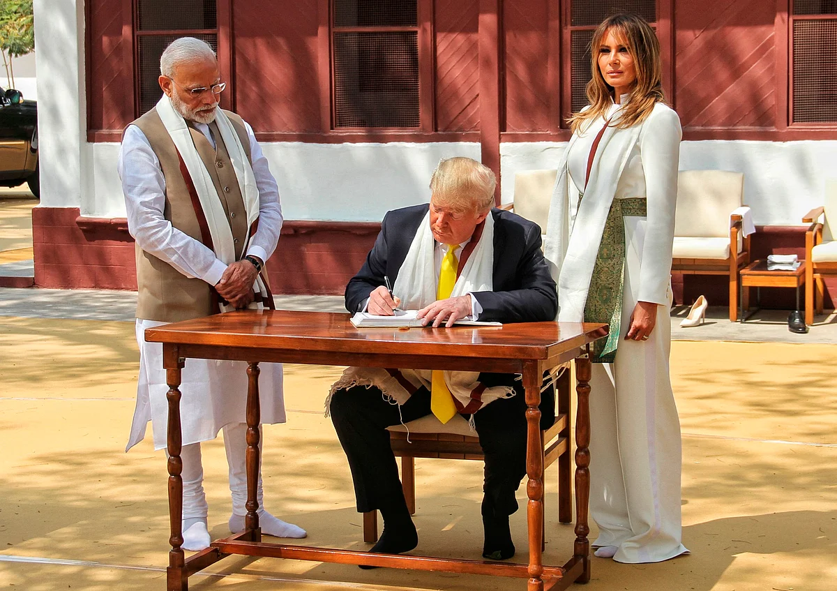 Photograph taken and released by India's Ministry of External Affairs (MEA) on February 24, 2020, US President Donald Trump signs the visitors book as First Lady Melania Trump and India's Prime Minister Narendra Modi (L) look on during their visit at Gandhi Ashram in Ahmedabad.