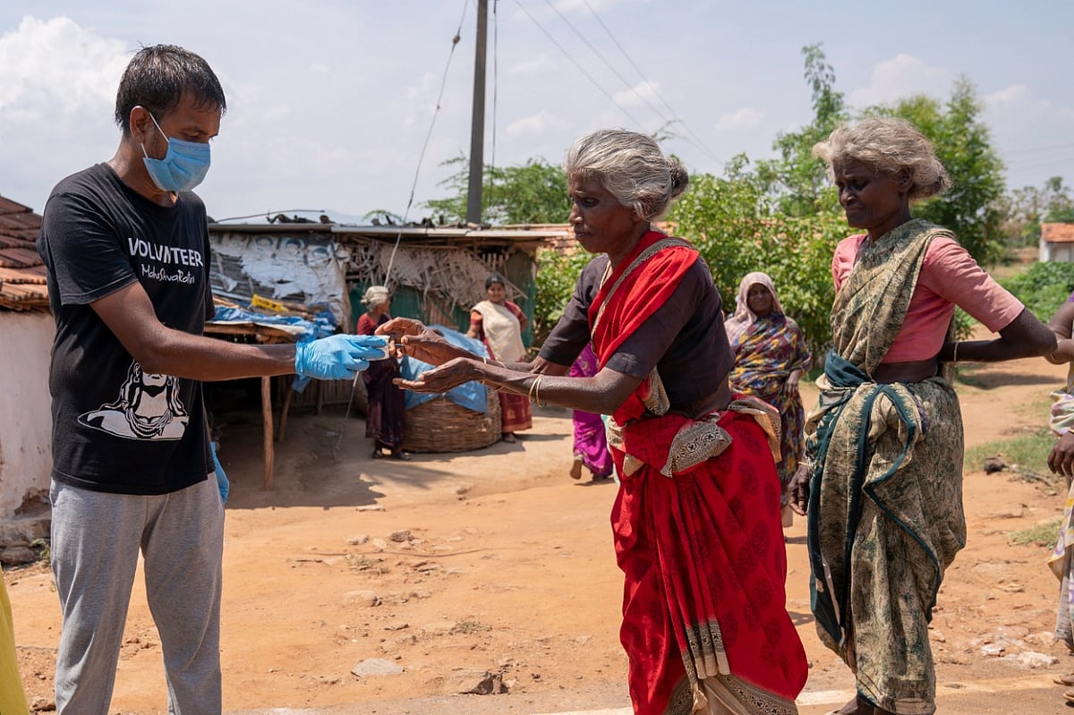 A villager accepts a token from an Isha Foundation volunteer