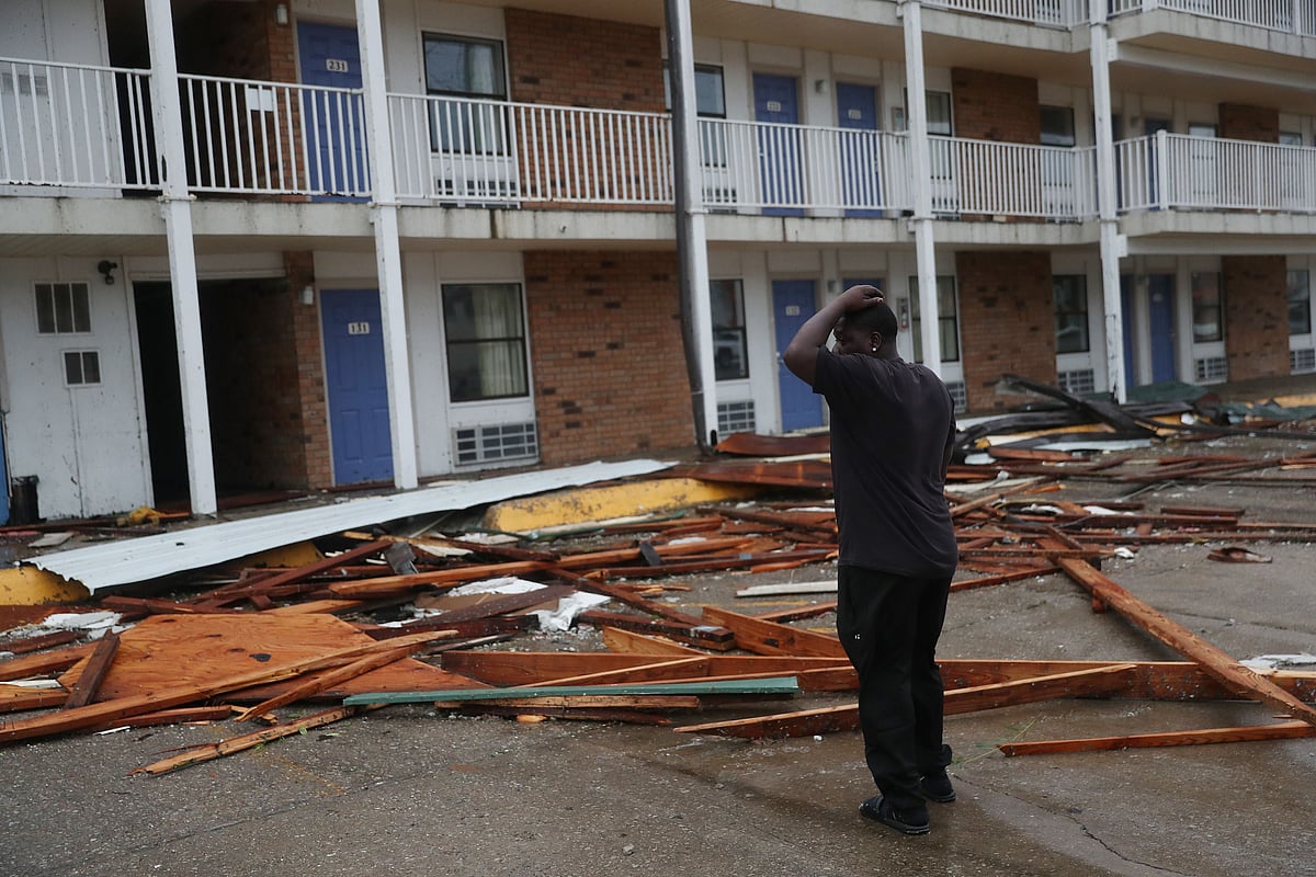 A person stands next to a hotel that had parts of its roof blown off as Hurricane Laura passed through the area on August 27, 2020 in Lake Charles, Louisiana .