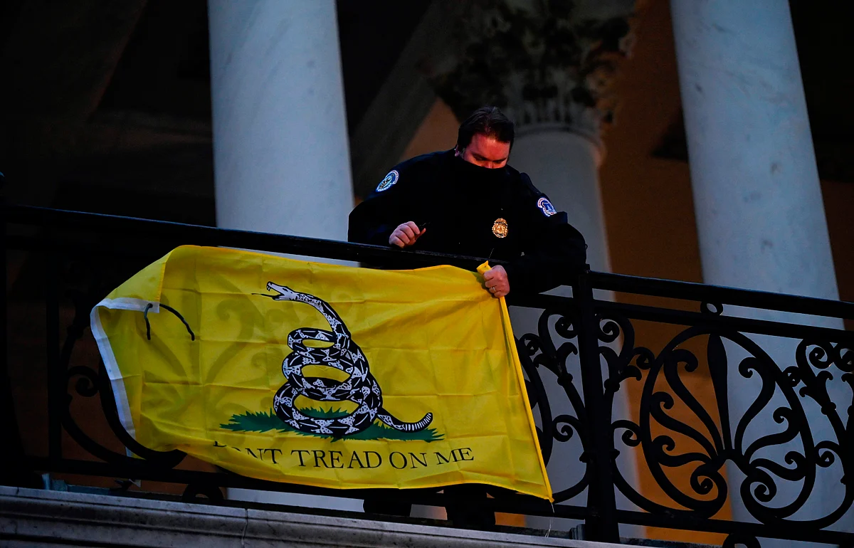 A police officer takes down a flag left hanging by protestors outside of the US Capitol in Washington DC on January 6, 2021.