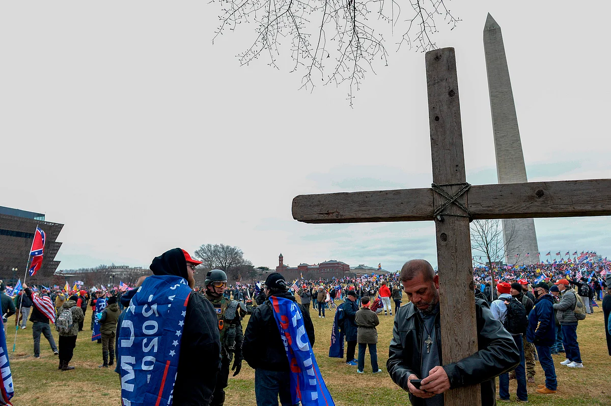 A man holds a large wooden cross near the Washington Monument during a rally in support of US President Donald Trump in Washington DC on January 6, 2021.