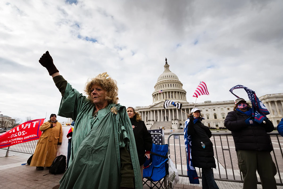 A protester dressed like the Statue of Liberty stands with a fist raised on the grounds of the Capitol Building on January 6, 2021 in Washington DC.