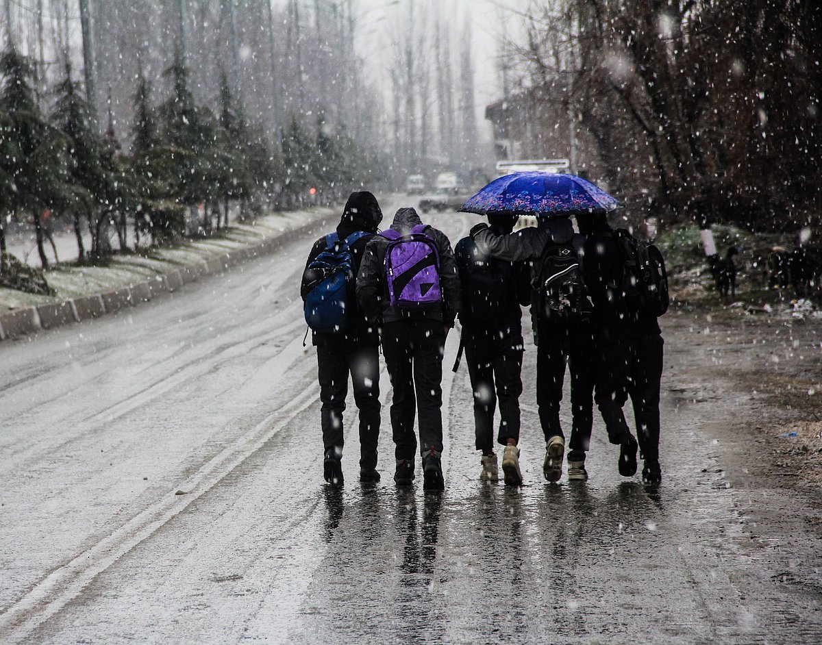 Children walking with umbrellas during fresh snowfall on March 08, 2021.
