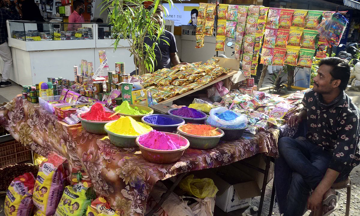 A vendor selling colours waits for customers in New Market ahead of Holi.