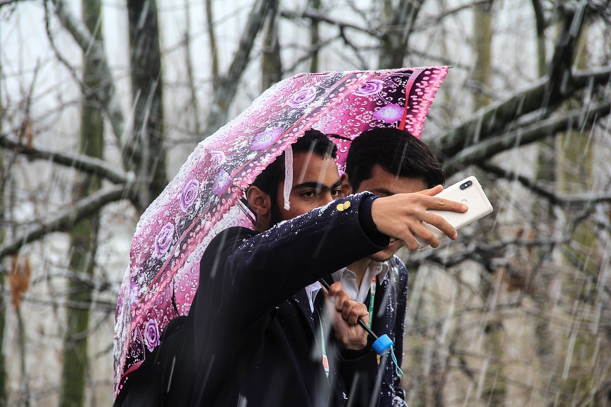 Children seen taking a selfie in a park during fresh snowfall in parts of Kashmir