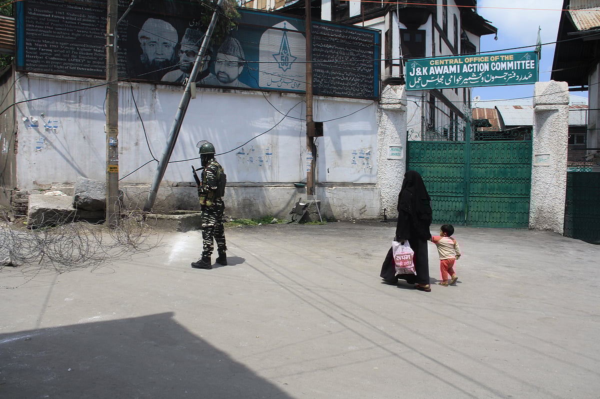 A woman walks past a security personnel during strict restrictions imposed on the death anniversaries of two separatist leaders Mirwaiz Mohammed Farooq and Abdul Ghani Lone, in Srinagar, Kashmir on May 21, 2021.