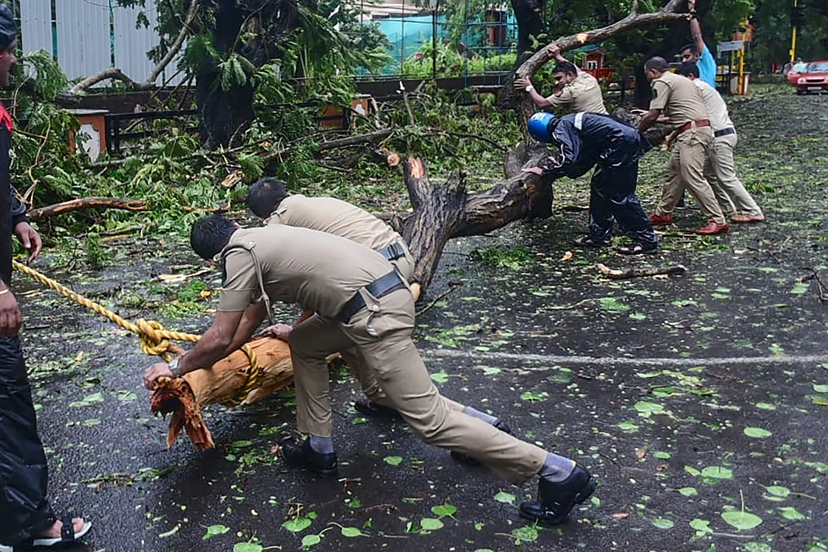 Police personnel clear fallen trees from a road following severe cyclonic storm Tauktae, at Panjim in Goa on May 16, 2021.