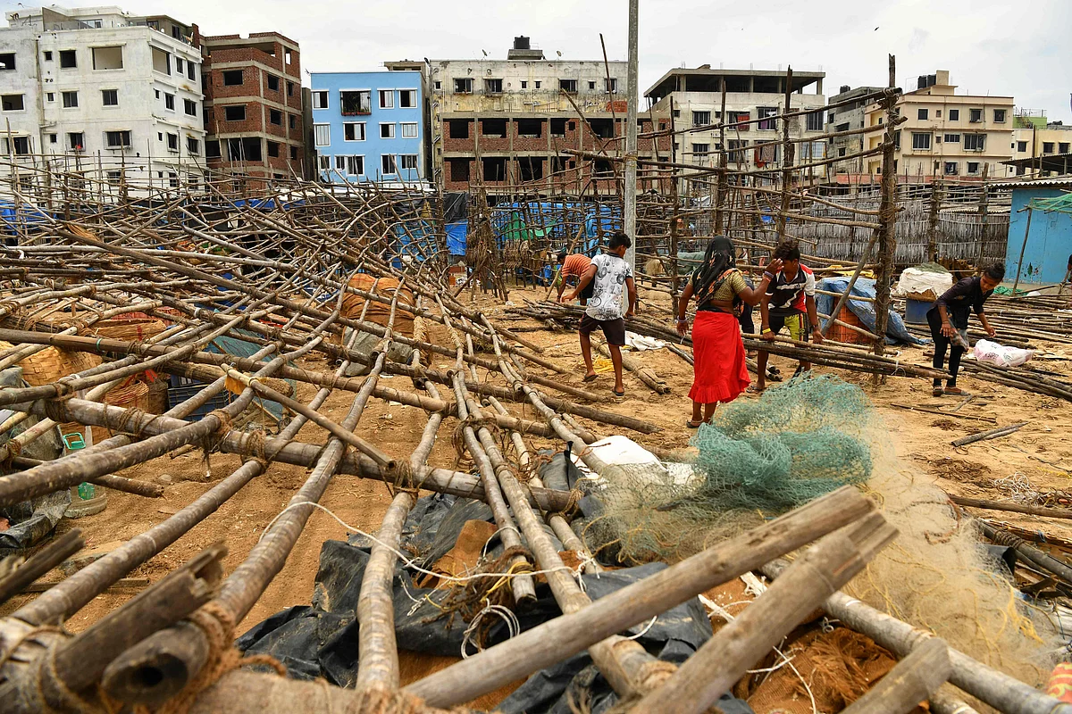Fisherfolk mend bamboo racks being used to dry fishes after they were brought down by strong winds caused by the impending cyclone Tauktae at a fishing village off the city coast in Mumbai on May 16, 2021.