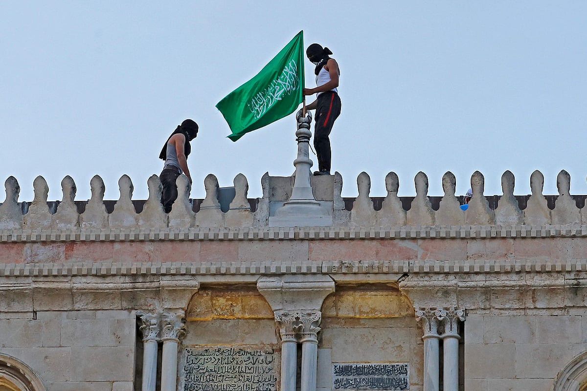Palestinians place the Hamas movement flag atop Jerusalems al-Aqsa mosque on May 10, 2021, amid clashes with Israeli scurity forces ahead of a planned march to commemorate Israels takeover of Jerusalem in the 1967 Six-Day War.