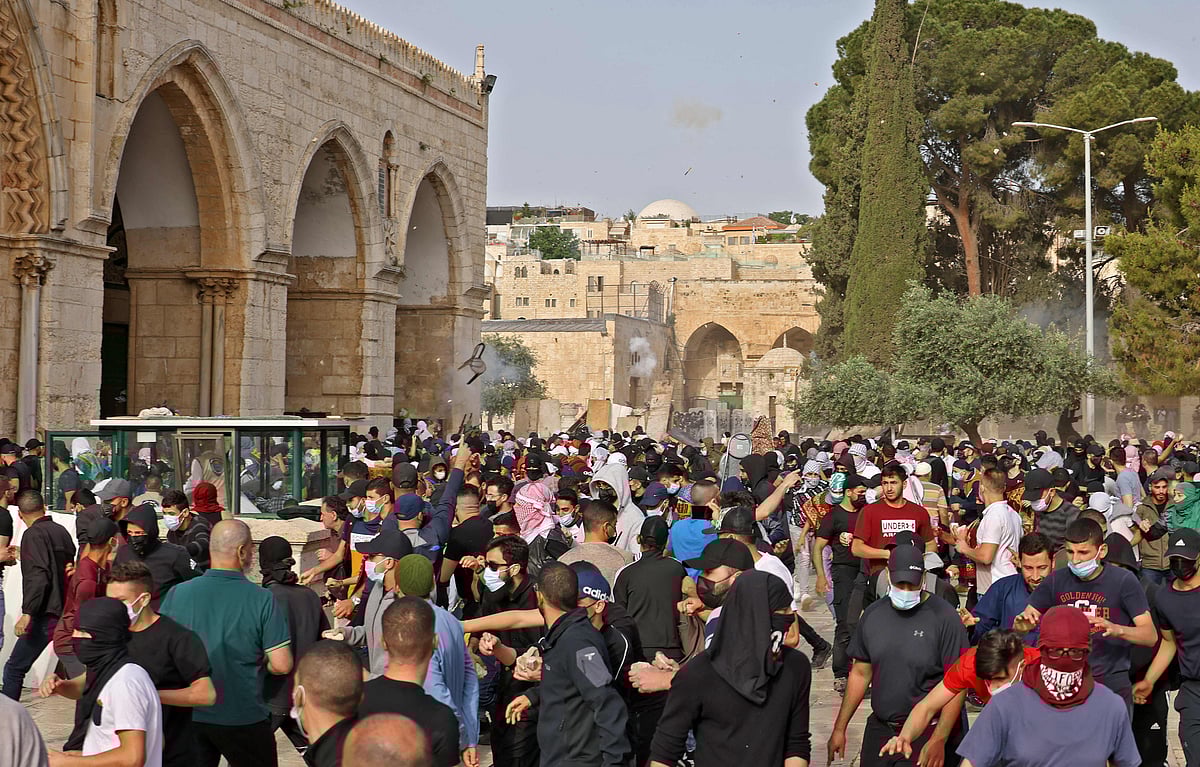 Palestinians run for cover from tear gas fired by Israeli security forces at Jerusalems Al-Aqsa mosque compound on May 10, 2021, ahead of a planned march to commemorate Israels takeover of Jerusalem in the 1967 Six-Day War.