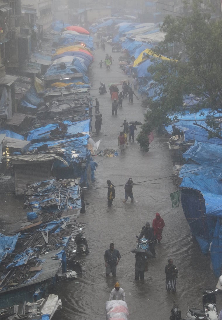 People trying to commute on a street completely waterlogged due to heavy rains