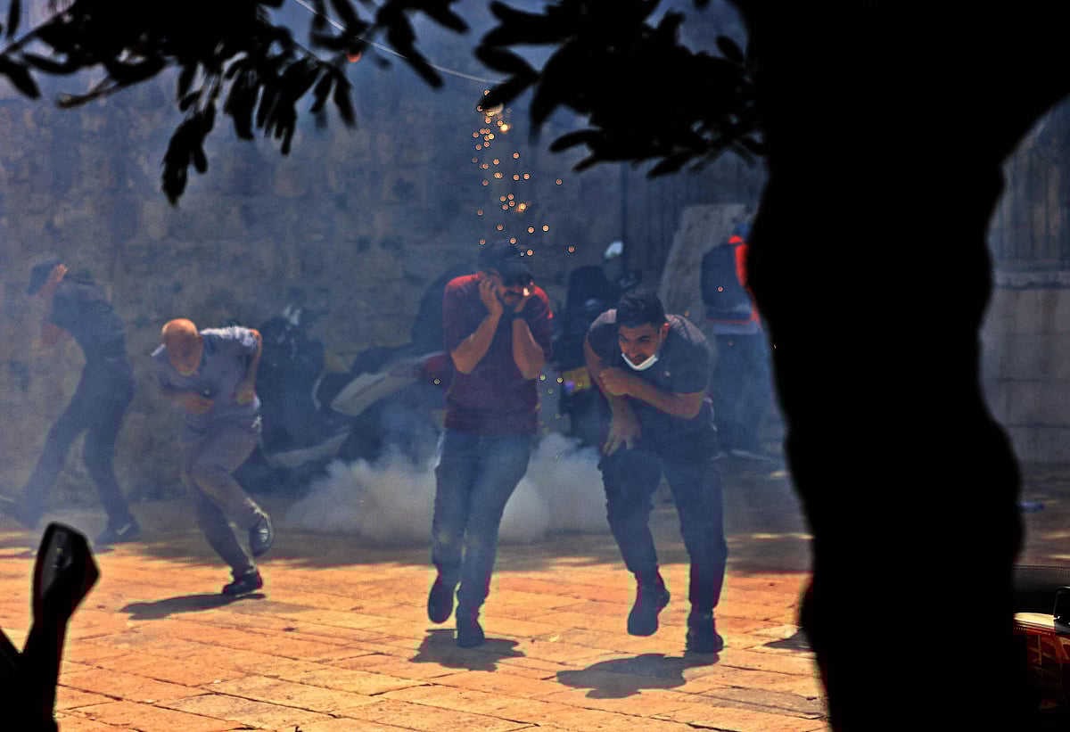 Palestinians run for cover from tear gas fired by Israeli security forces in Jerusalems Old City on May 10, 2021, ahead of a planned march to commemorate Israels takeover of Jerusalem in the 1967 Six-Day War.