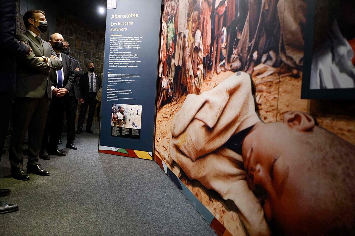 Macron (L) and French European and Foreign Affairs Minister Jean-Yves Le Drian stop to look at images during their visit to the Kigali Genocide Memorial, where some 250,000 victims of the massacres are buried, in Kigali on May 27