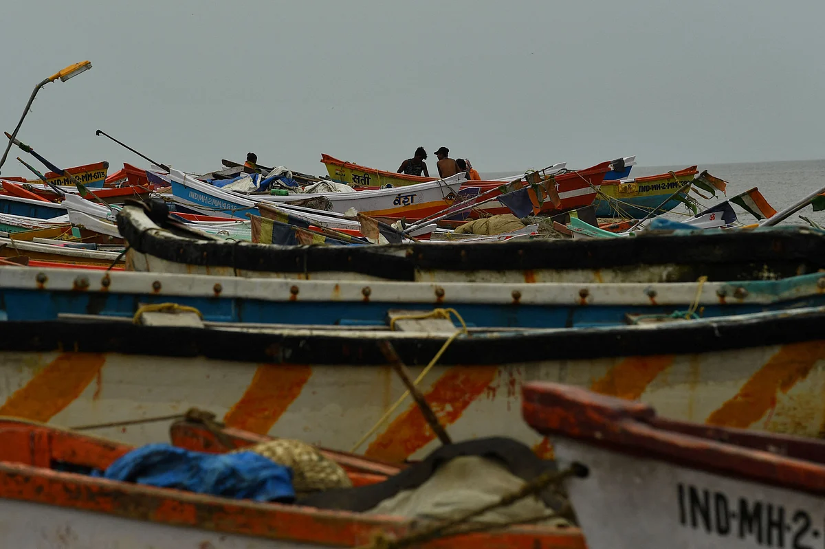 Fishermen are seen next to boats being moored at a fishing village off the city coast in the wake of the impending cyclone Tauktae in Mumbai on May 16, 2021.