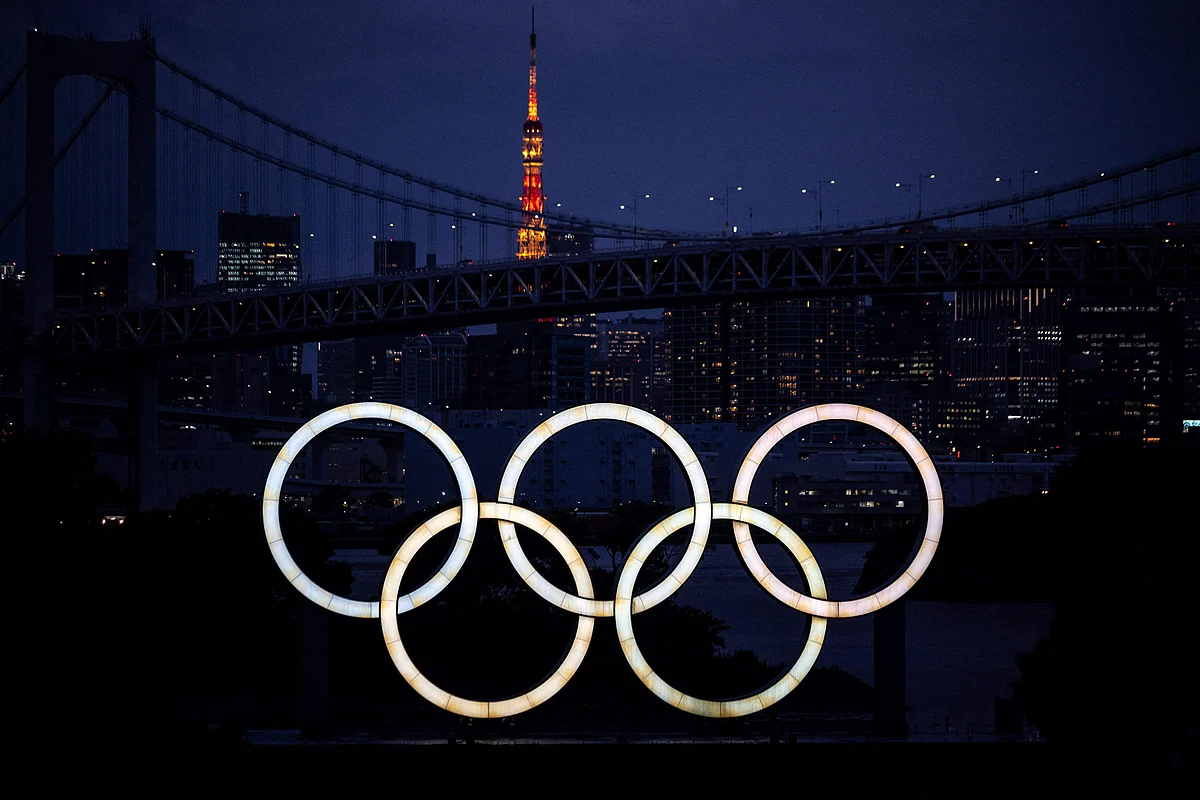 A general view shows the Olympic Rings lit up at dusk, with the Rainbow bridge and the Tokyo Tower in the background, on the Odaiba waterfront in Tokyo on June 23, 2021.