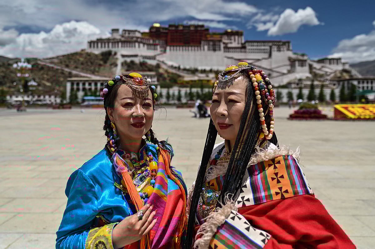 This photograph taken during a government organised media tour shows people in traditional costume standing in Potala Palace Square as the Potala Palace is seen in the background in the regional capital Lhasa, in China's Tibet Autonomous Region, on June 1, 2021. 