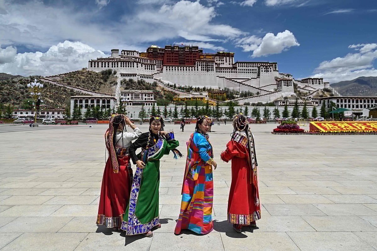 This photograph taken during a government organised media tour shows people in traditional costume standing in Potala Palace Square as the Potala Palace is seen in the background in the regional capital Lhasa, in China's Tibet Autonomous Region, on June 1, 2021.