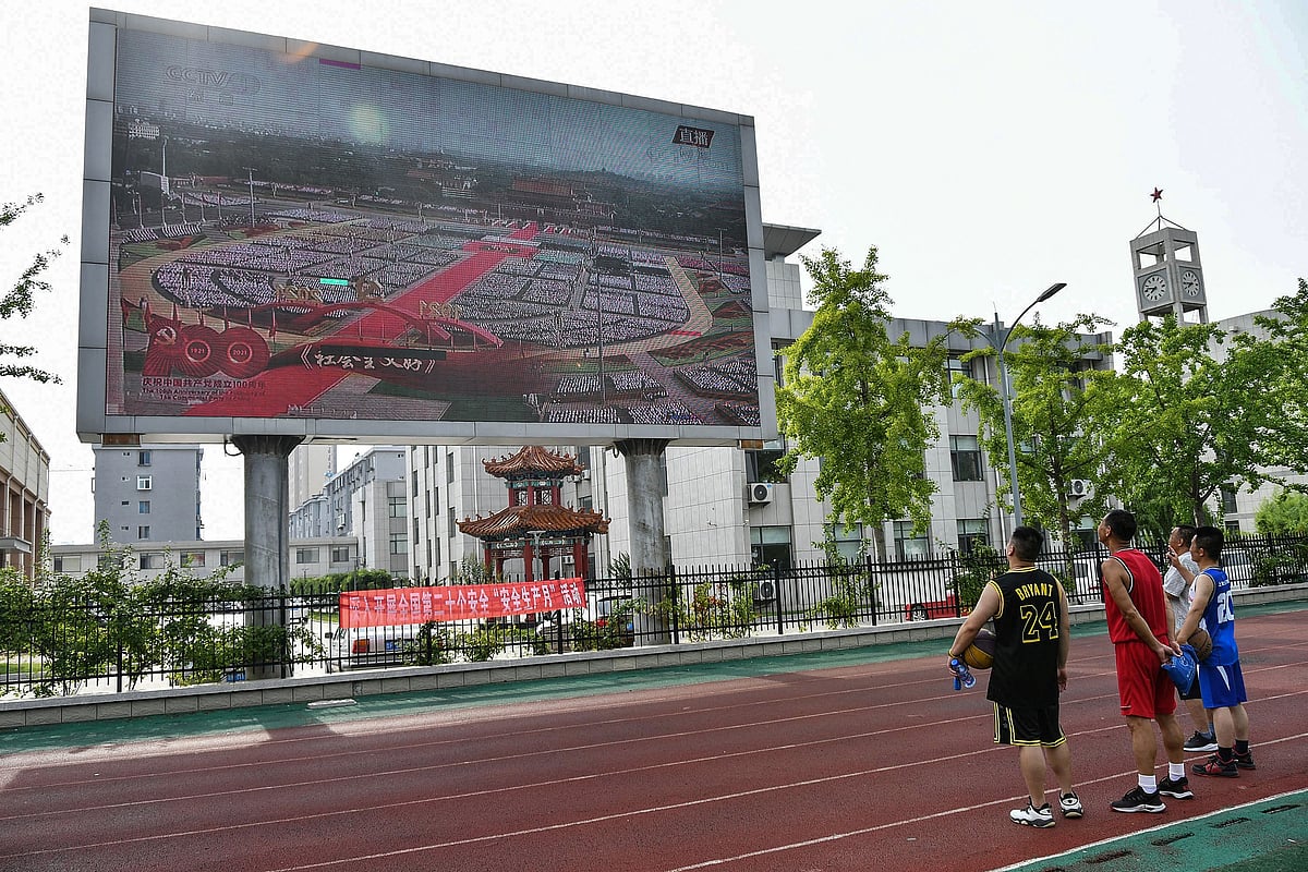 People watch a large screen showing the celebrations to mark the 100th anniversary of the founding of the Communist Party of China in Yantai, in Chinas eastern Shandong province on July 1, 2021.