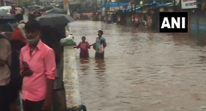 People wade through flooded roads as heavy rains flood Nalasopara