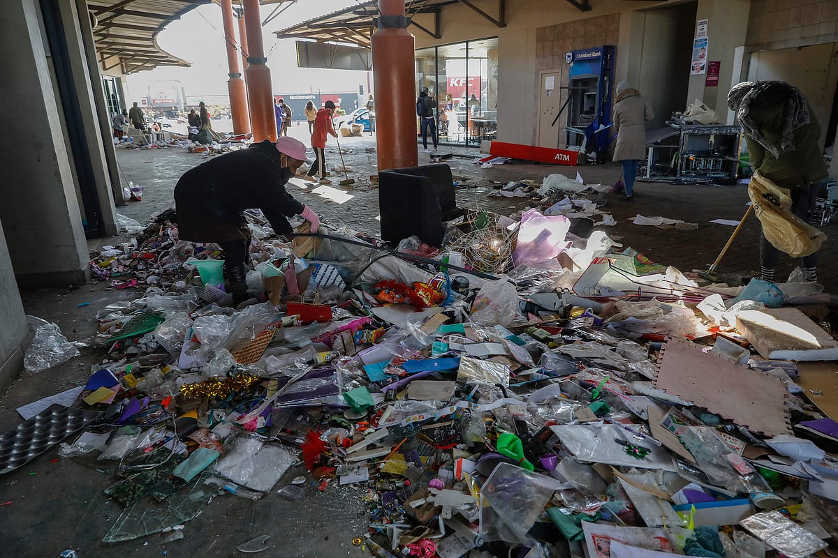 Locals use brooms while volunteering to clean the Diepkloof Square following looting and vandalism in Soweto, Johannesburg on July 14, 2021.