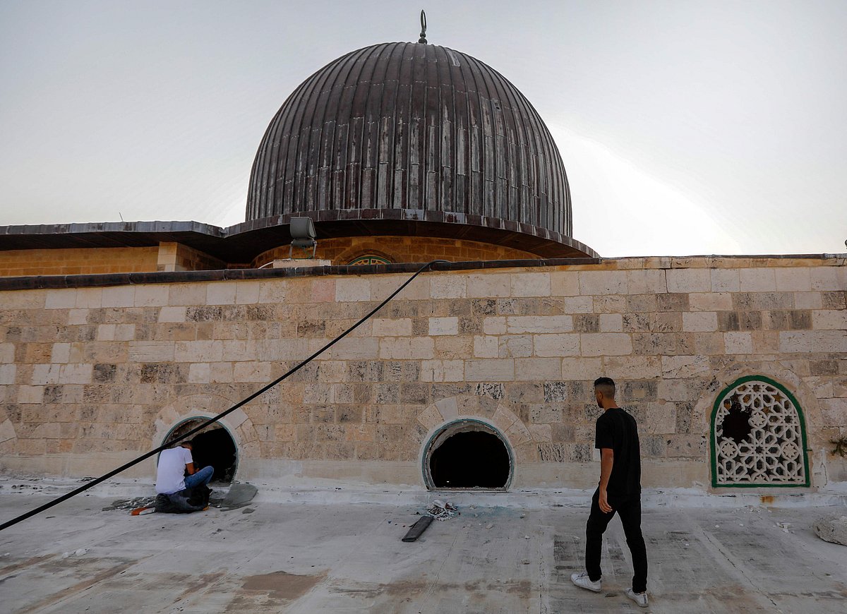 Palestinian youths look into the Al-Aqsa mosque on the first day of the Eid al-Adha feast celebrated by Muslims worldwide, on July 20, 2021, through windows which were shattered two days earlier in renewed clashes between Palestinians and Israeli police at the Al-Aqsa complex in Jerusalems old city.