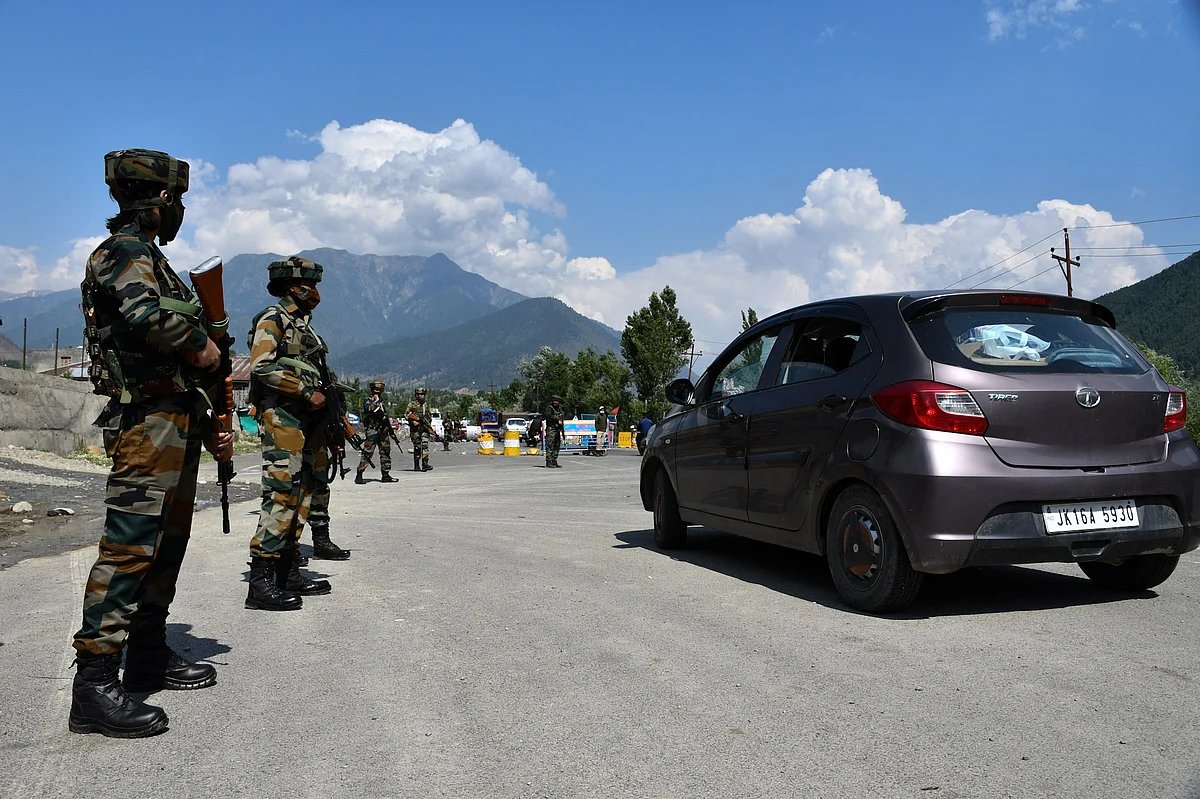 The soldiers stand on guard alongside passing vehicle