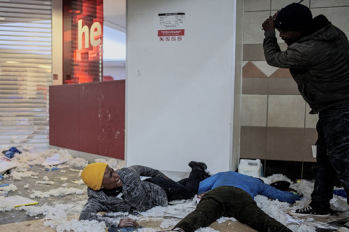 The owner of a shop (R) in Bara Mall beats suspected looters in Soweto on July 13, 2021.