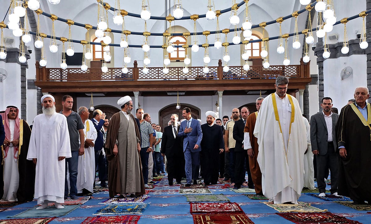 A handout picture released by the official Facebook page of the Syrian Presidency shows President Bashar al-Assad (C) performing Eid al-Adha prayer at Khaled bin al-Walid mosque in Homs on July 20, 2021.