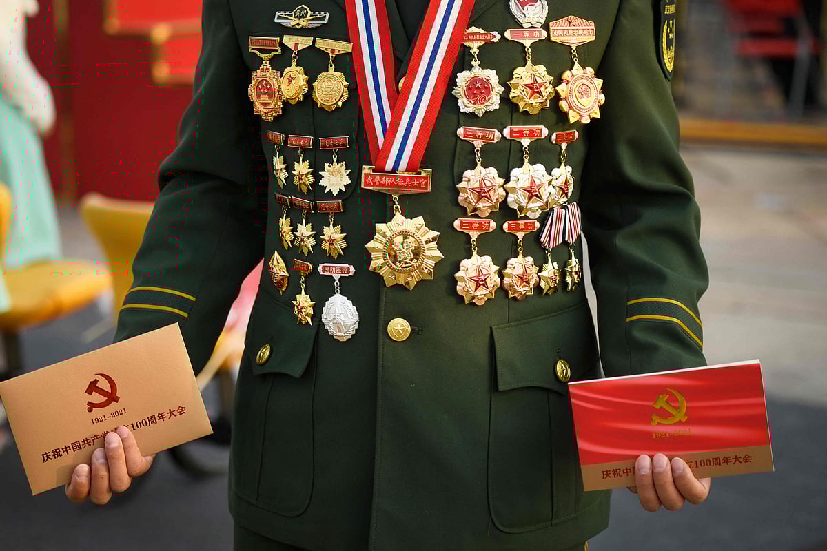 A attendee poses for a picture with military medals before the celebrations marking the 100th anniversary of the founding of the Communist Party of China in Beijing on July 1, 2021.