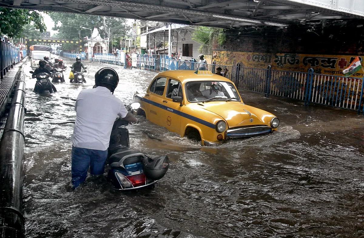 West Bengal, July 30 (ANI): Commuters wade through a waterlogged road after heavy rainfall at Patipukur Railway Bridge, in Kolkata on Friday.