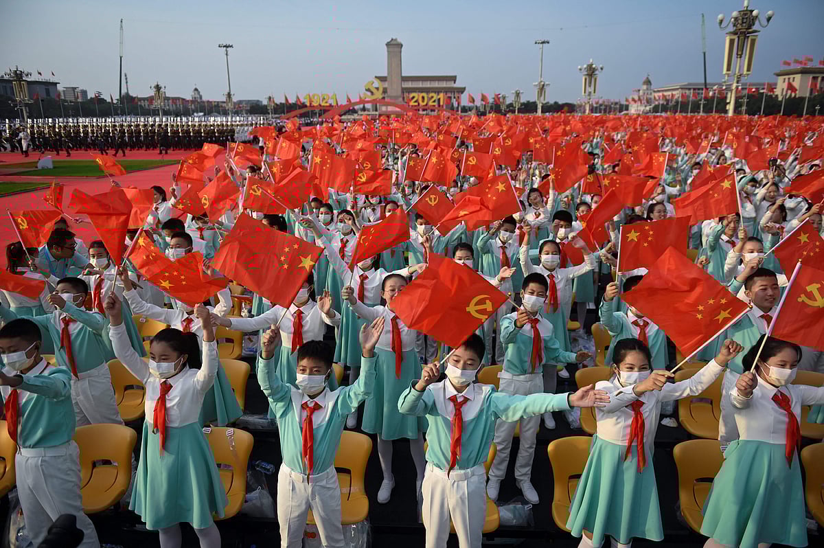 Students wave Chinese flags before the celebration of the 100th anniversary of the founding of the Communist Party of China at Tiananmen Square in Beijing on July 1, 2021.