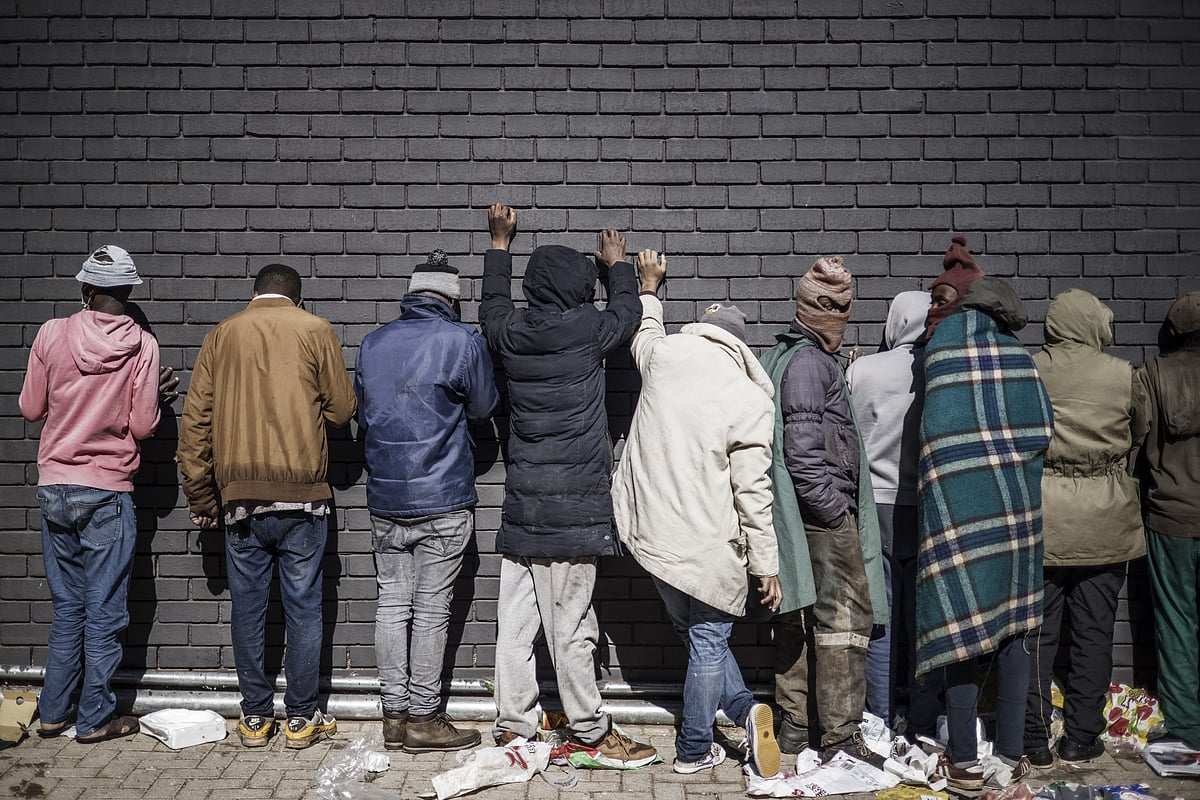 Suspected looters, rounded up by the South Africa police Services (SAPS) and local private security officers lean against a wall after being caught red handed and detained in Vosloorus, on July 13, 2021.