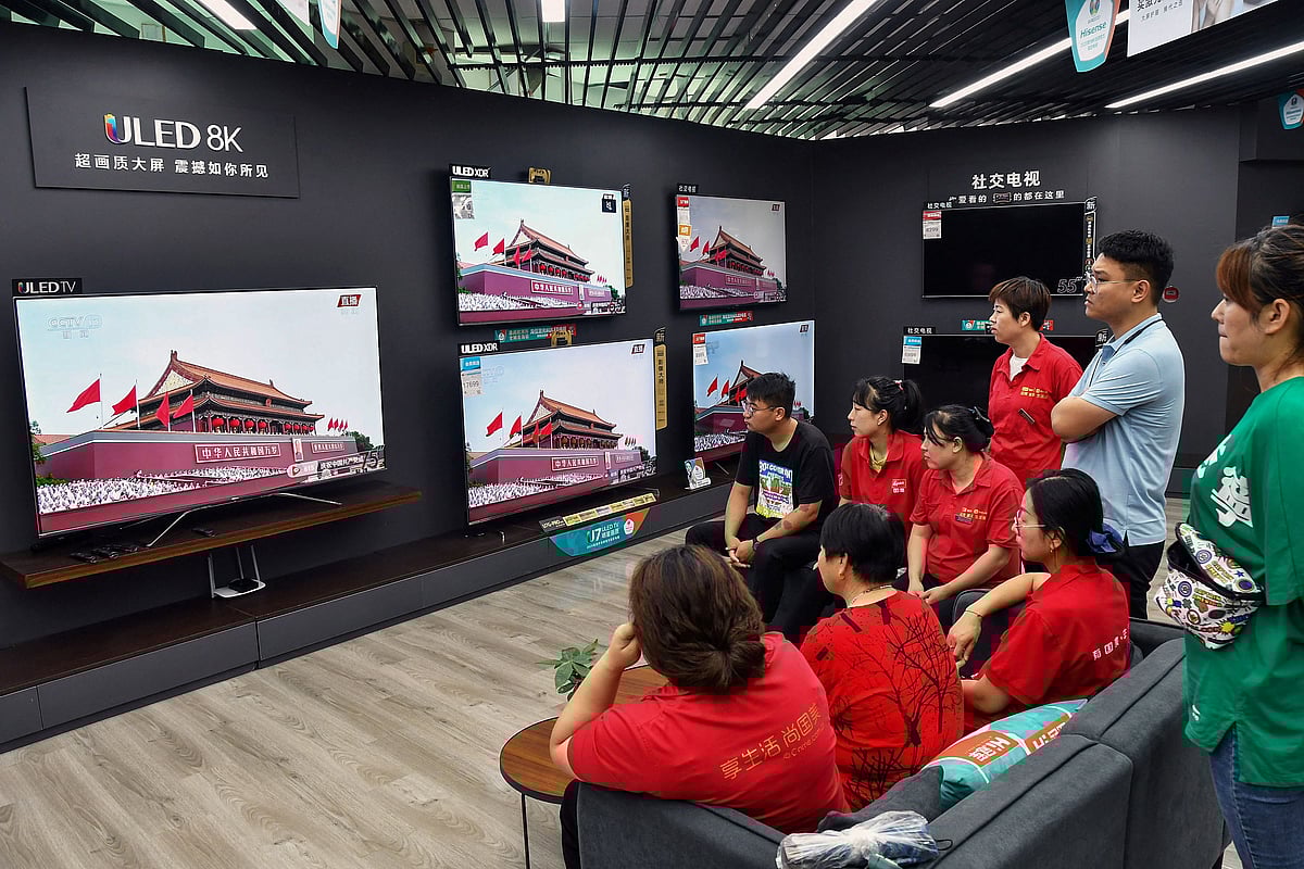 Staff members and customers watch a television showing the celebrations to mark the 100th anniversary of the founding of the Communist Party of China at a shopping mall in Yantai, in Chinas eastern Shandong province on July 1, 2021.