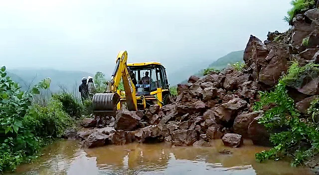 Maharashtra, July 22: A JCB removes the fallen rocks due to landslides following heavy rainfalls and block the road, in Pune on Thursday.