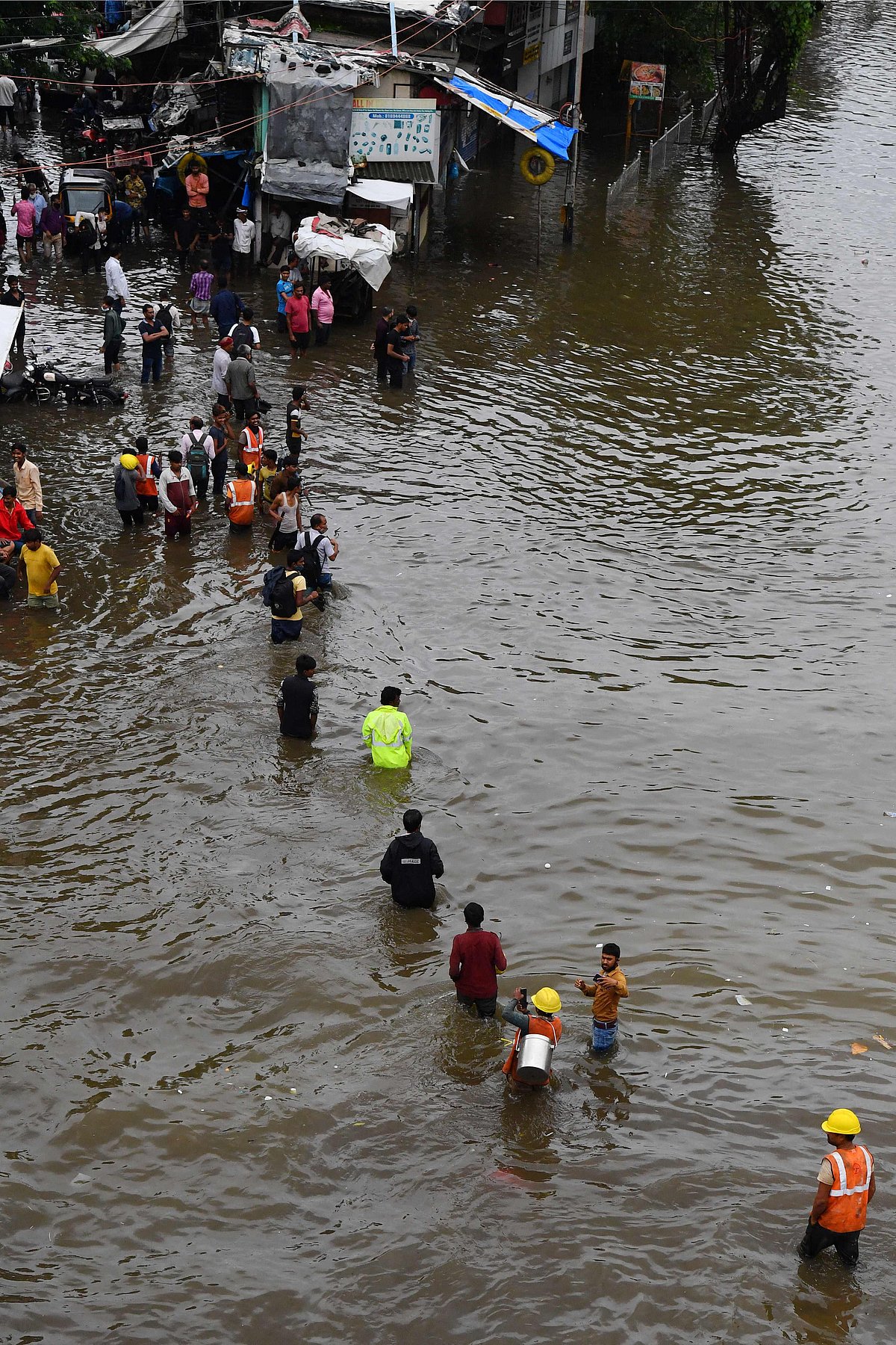 People wade along a waterlogged street following a heavy monsoon rainfall in Mumbai on July 16, 2021.