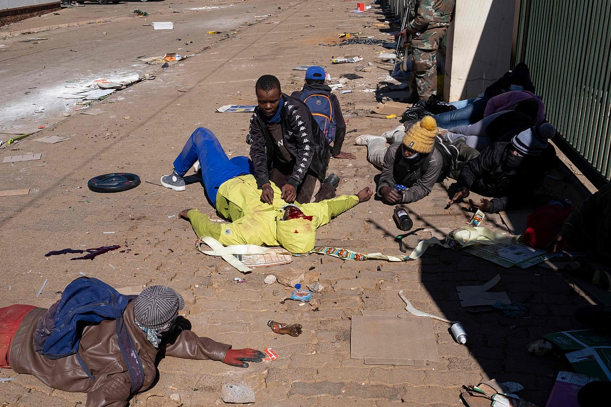 A suspected looter who was allegedly wounded by rubber bullets shot by Jabulani Mall security personnel lies on the ground in Soweto on the outskirts of Johannesburg on July 13, 2021.