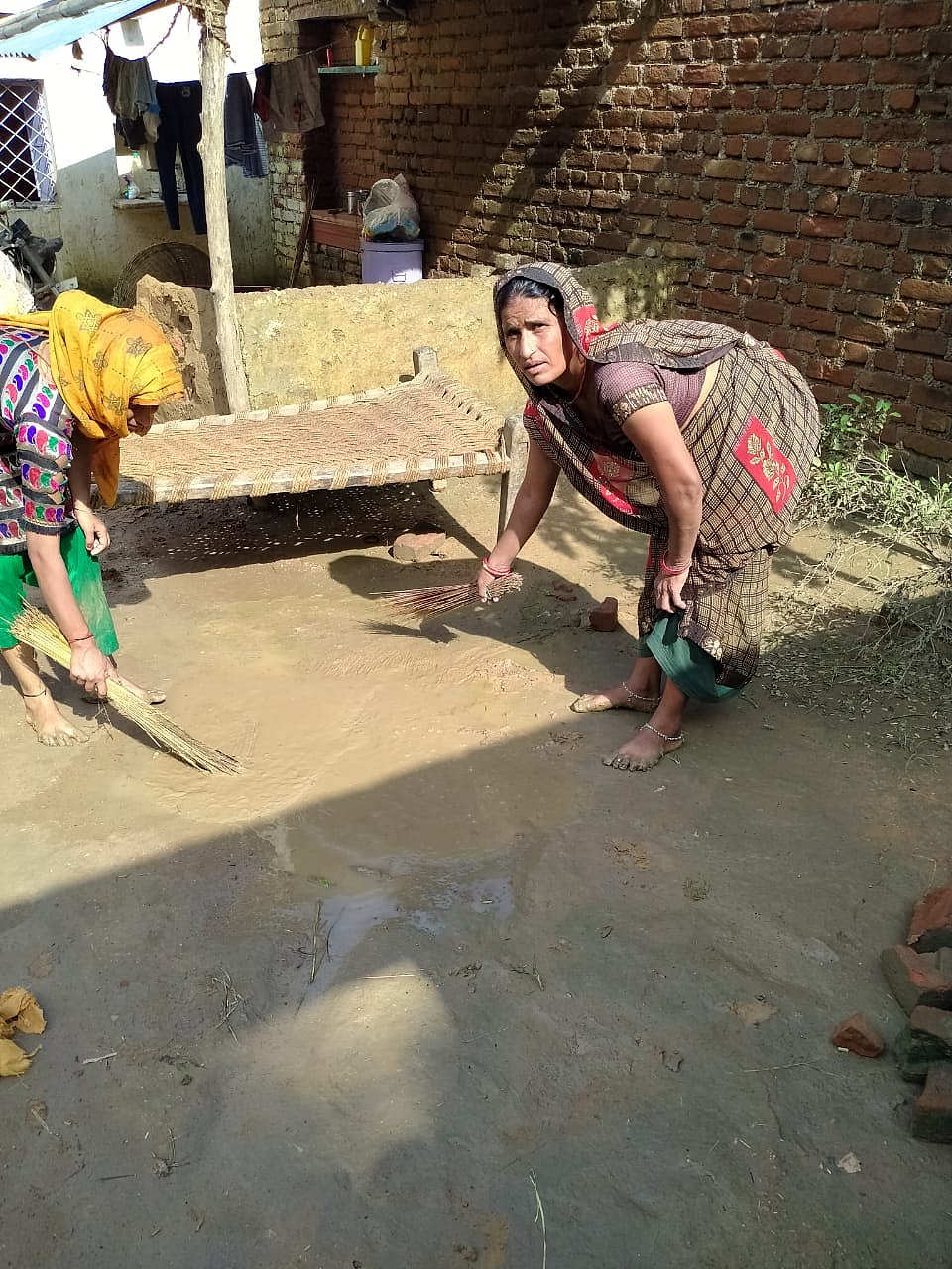 Women removing sludge accumulated after the flood-water receded