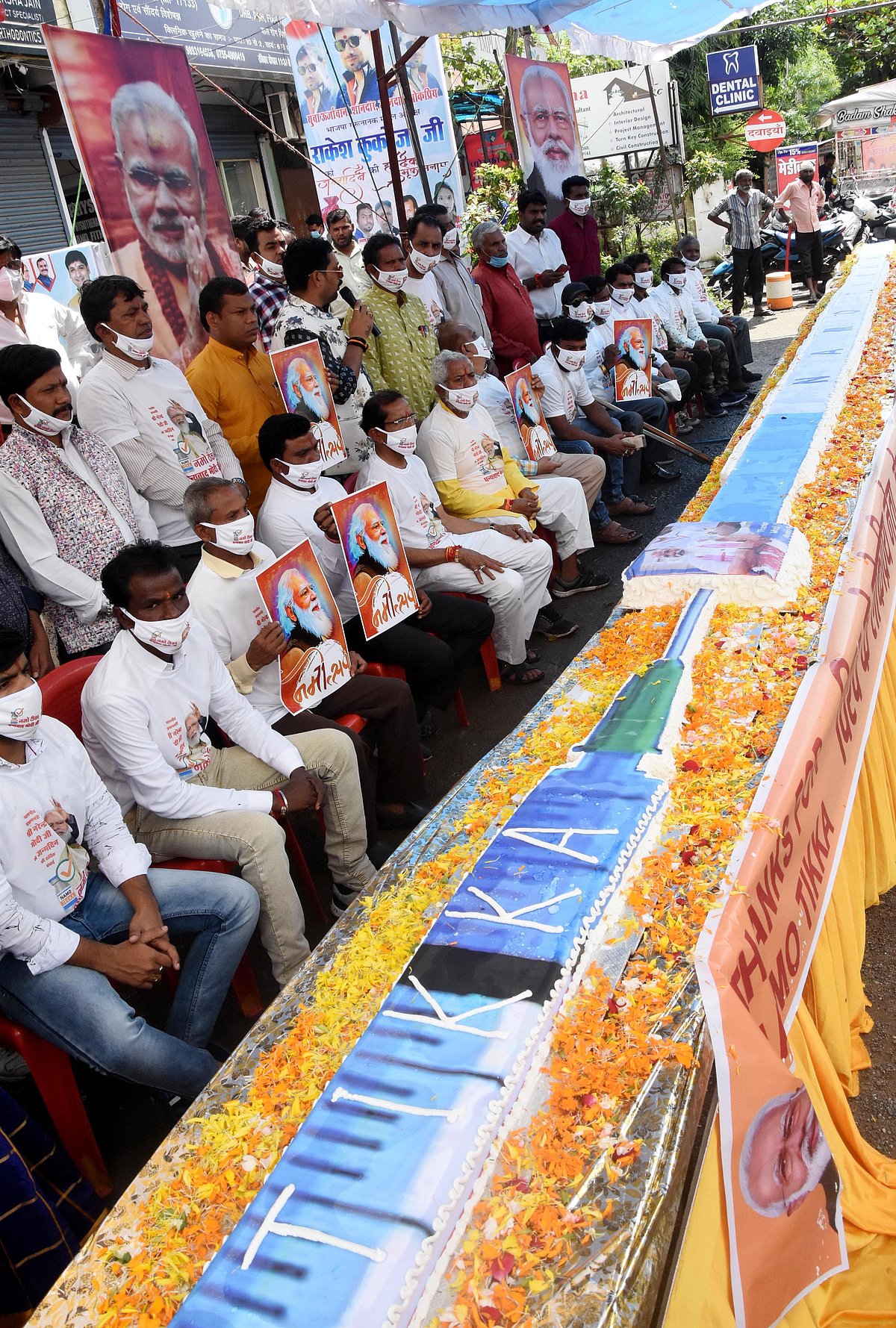 Party workers cut a 71-foot -long cake prepared in the shape of a vaccine syringe at Lalghati square