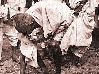 Gandhi ceremoniously breaking the salt law by picking up a lump of natural salt at Dandi on Apirl 6, 1930