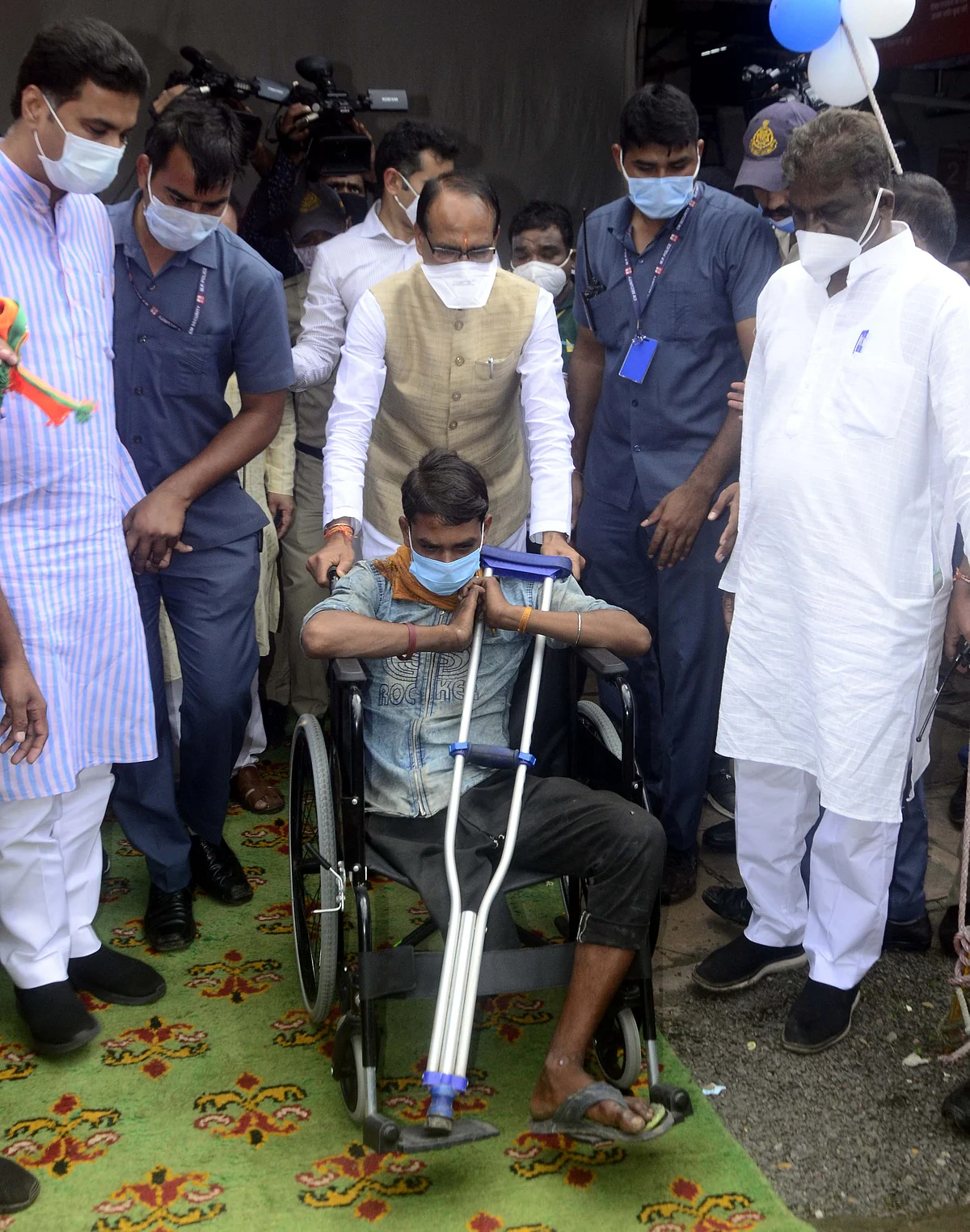 Madhya Pradesh Chief Minister Shivraj Singh Chouhan helps a specially abled beneficiary, during the launch of a mega vaccination drive, in Bhopal, Friday