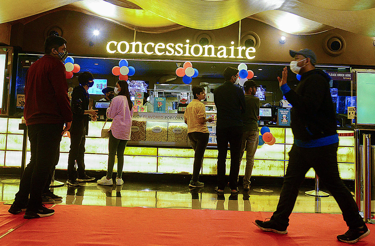 Cinema-goers queue up to buy snacks during intermission time at a cinema theatre in Mumbai on October 22, 2021