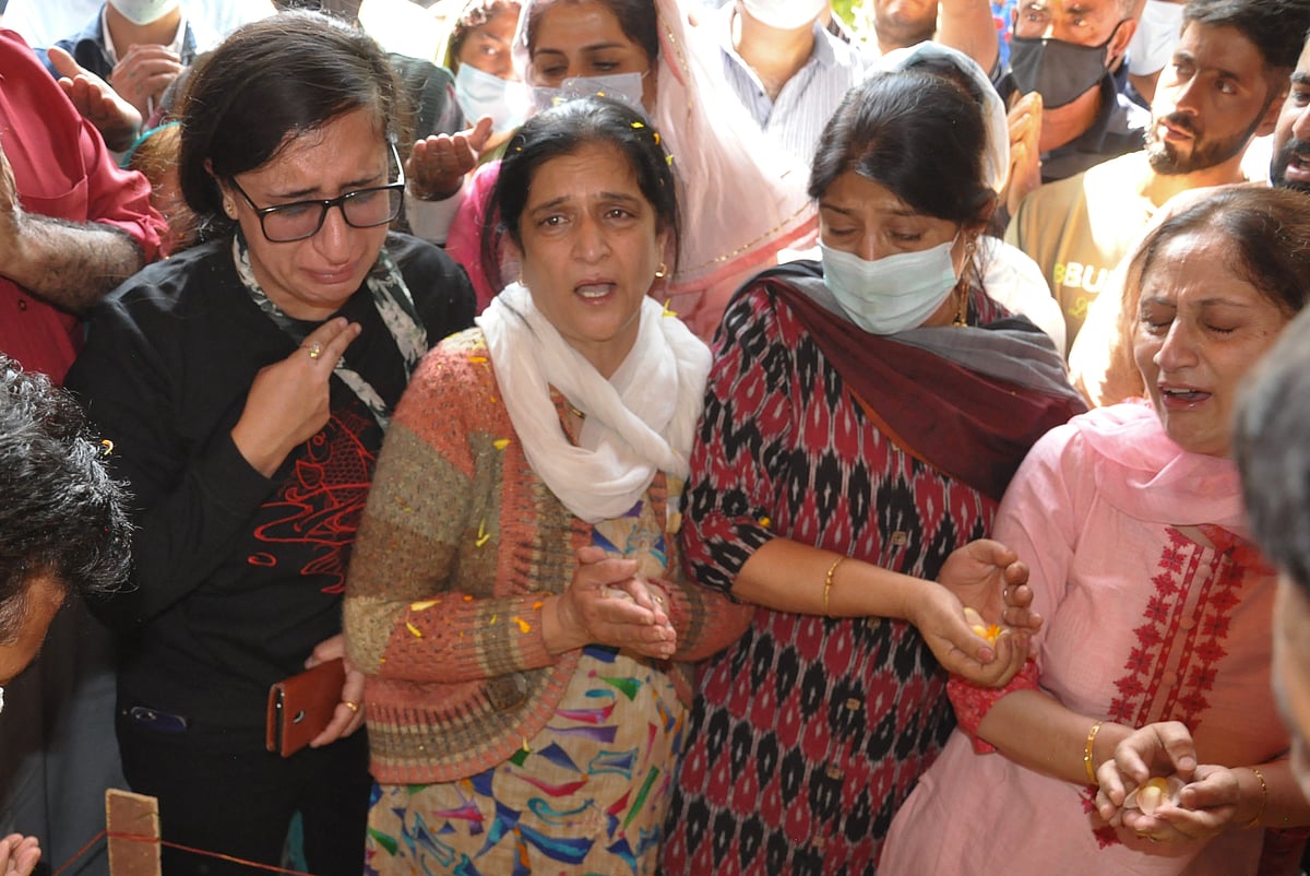 Daughter Shraddha (L), wife (2L) of Makhan Lal Bindroo, a prominent pharmacist, mourns around his body along with other relatives during his funeral at his residence in Srinagar, Kashmir on Wednesday, October 6, 2021.