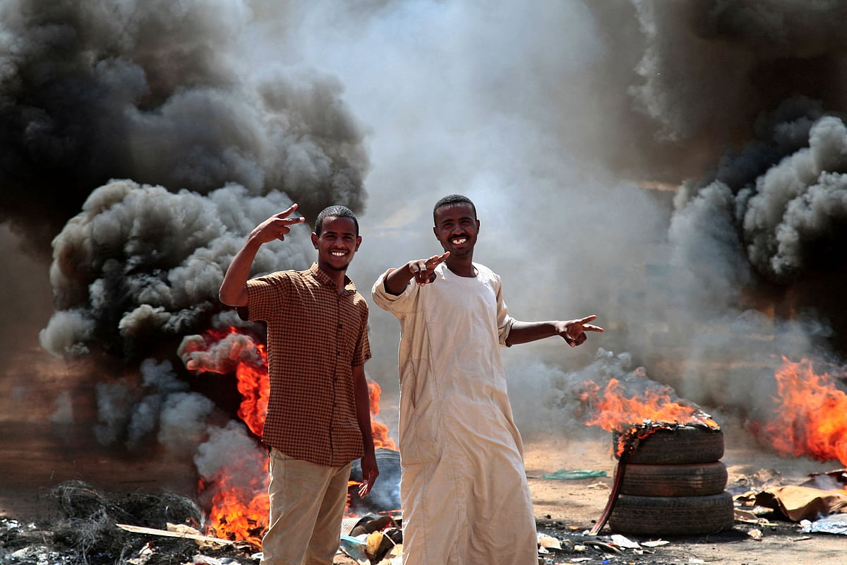 Sudanese demonstrators flash victory signs by a roadblock made of buring tyres in the capital Khartoum, on October 26, 2021, as they protest a military coup that overthrew the transition to civilian rule. 
