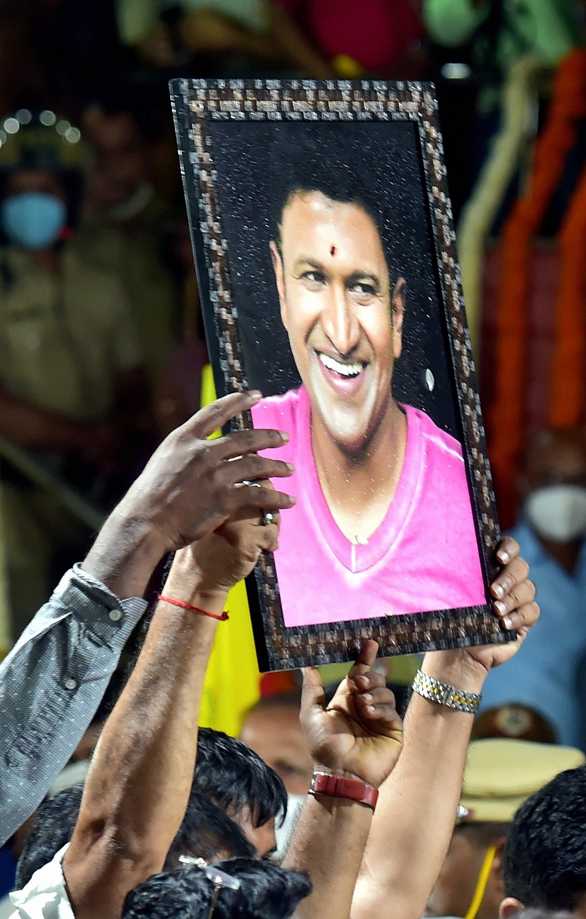 Bengaluru: A fan holds a poster of Kannada film actor Puneeth Rajkumar as he arrives to pay his last respects to the mortal remains of Rajkumar at the Kanteerava Stadium, in Bengaluru, Friday, Oct. 29, 2021. Rajkumar passed away due to a fatal cardiac arrest on Friday morning.