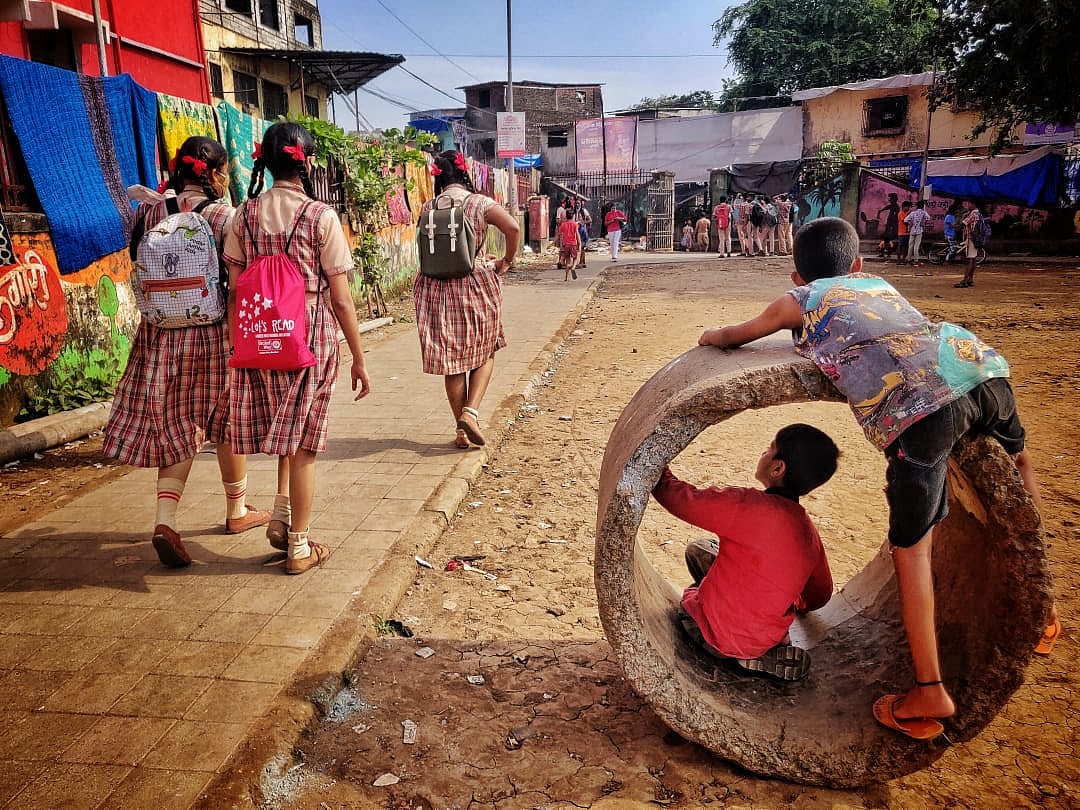 Some students walk towards school while other kids play nearby in Dharavi, Mumbai on Tuesday, October 5, 2021.