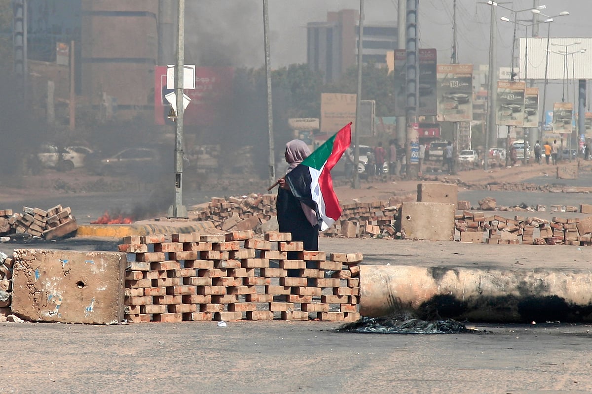 A Sudanese demonstrator carrying a national flag walks by roadblocks set up by protesters on a street in the capital Khartoum, on October 26, 2021, to denounce a military coup that overthrew the transition to civilian rule. 