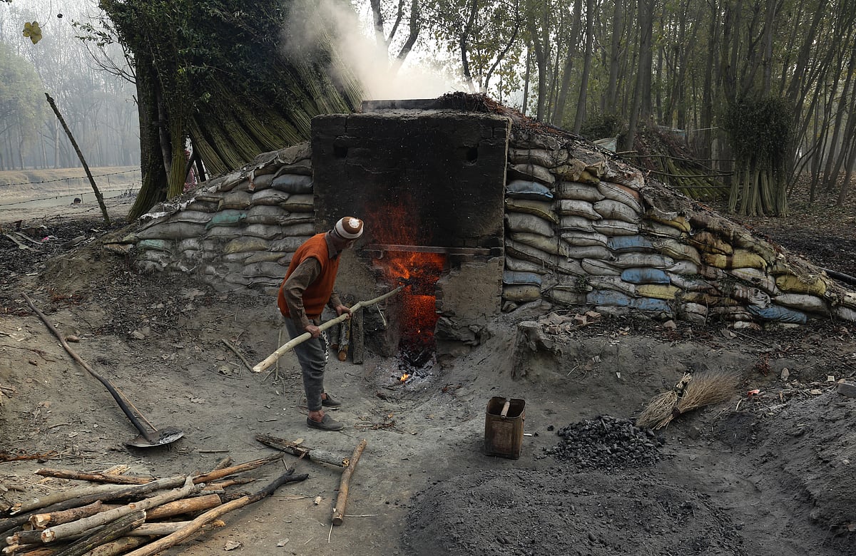 A worker uses firewood to boil wicker twigs in the boiler on the outskirts of Srinagar, Jammu and Kashmir.