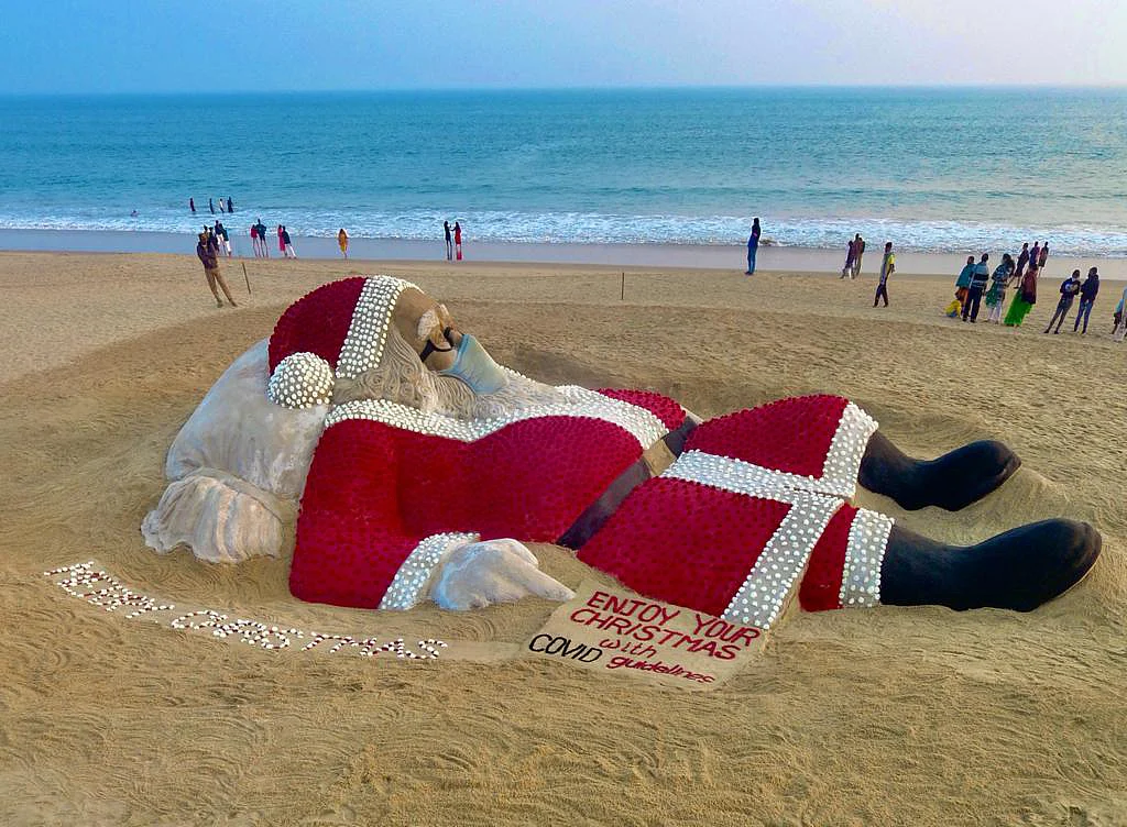 Puri: Renowned sand artist Sudarsan Pattnaik creates a sand Santa Claus with an installation of red roses and other flowers with the message ?Merry Christmas, Enjoy your Christmas with COVID guidelines ?, at Puri beach of Odisha, Friday, Dec. 24, 2021.